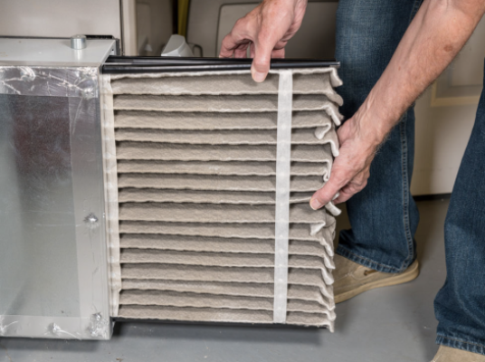 Man replacing dirty air filter in furnace.