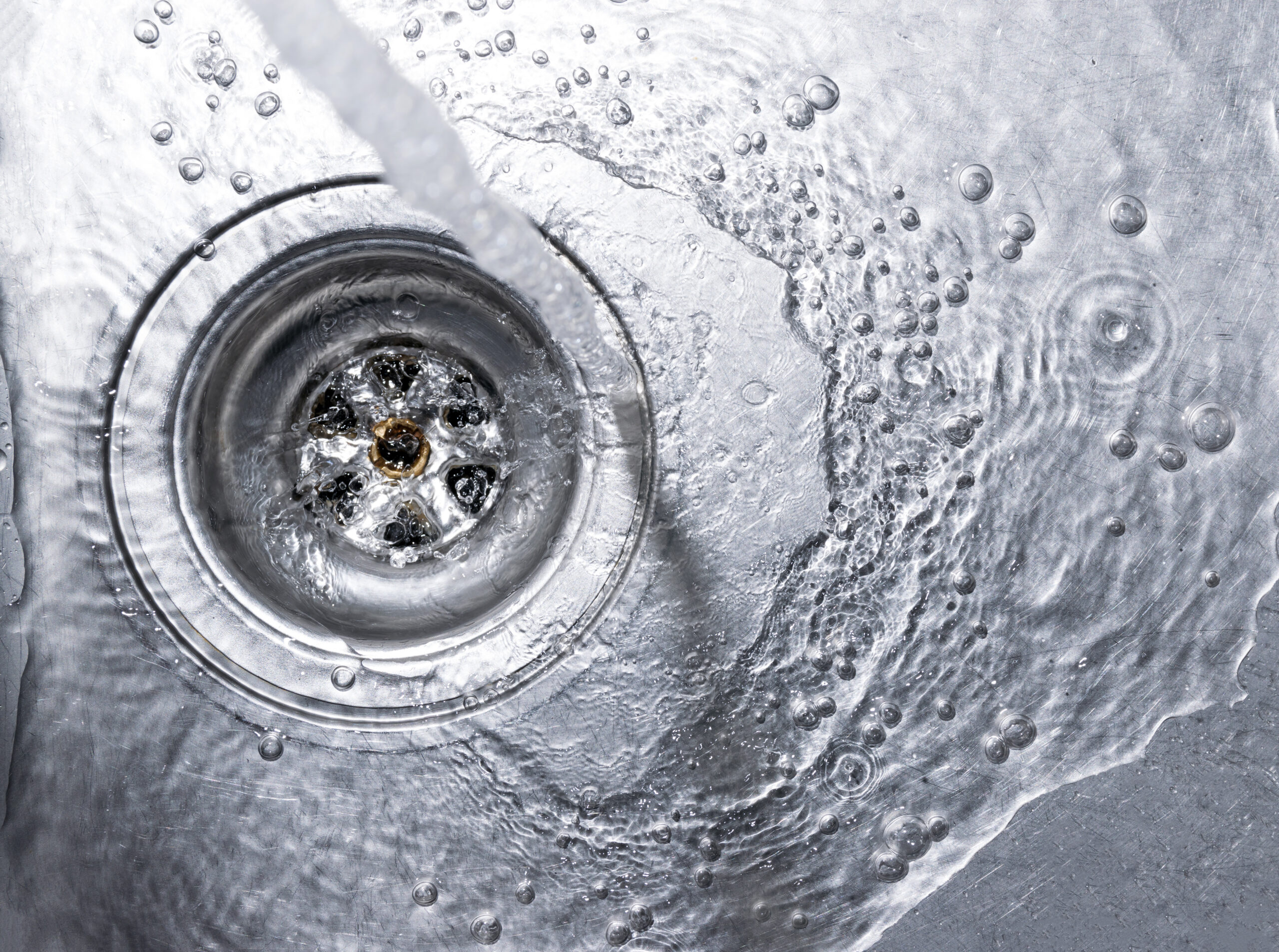 Running water drains down a stainless steel sink.