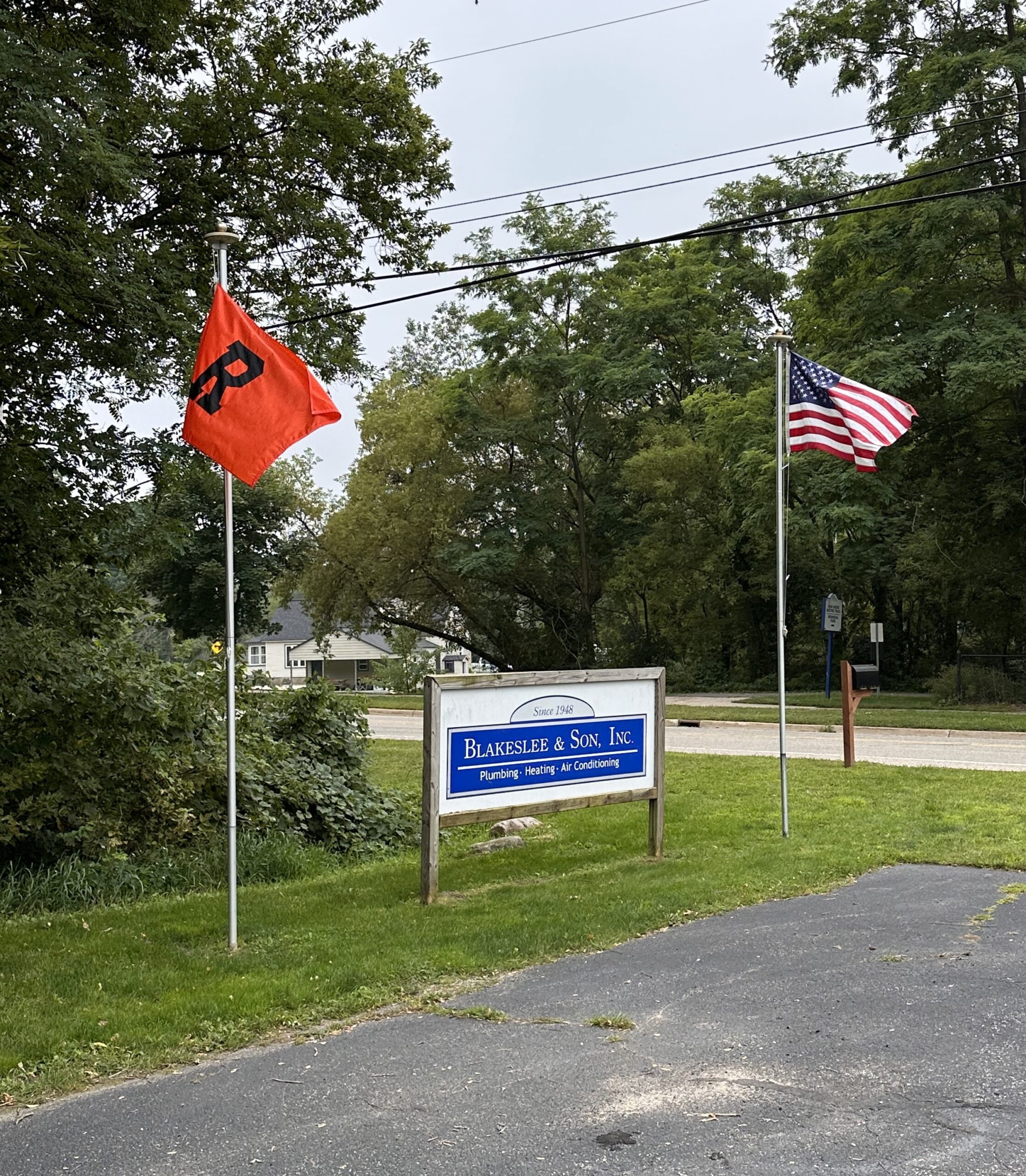 The Blakeslee sign outdoors alongside the American flag and the Blakeslee flag